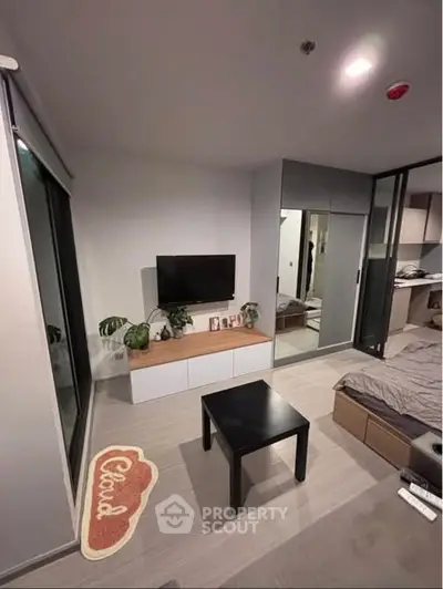 Modern bedroom with TV and sliding glass doors, featuring sleek furniture and decor.