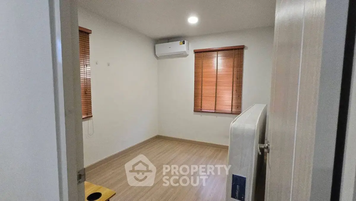Cozy unfurnished room with wooden flooring and air conditioning unit.