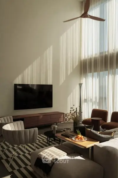 Luxurious living room with high ceilings, modern furniture, and large TV, bathed in natural light.