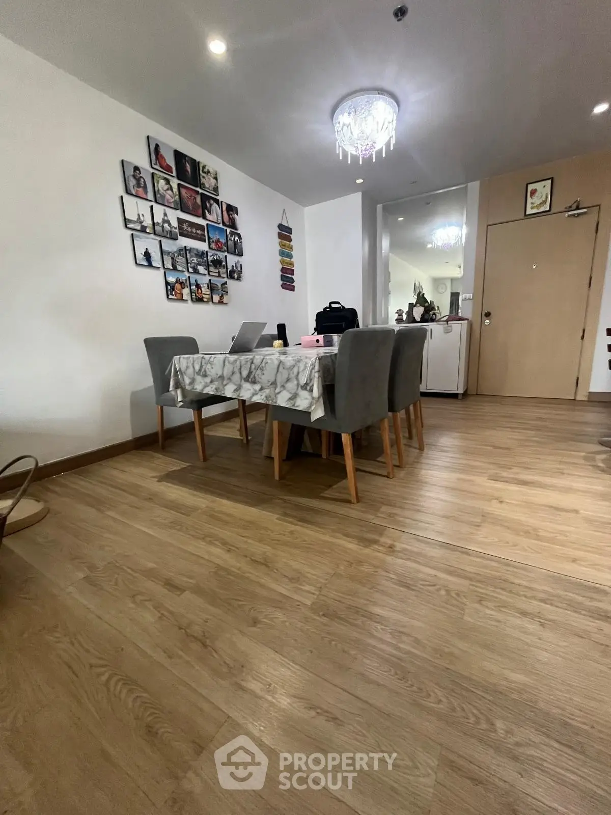 Stylish dining area with elegant chandelier and wooden flooring in modern apartment.