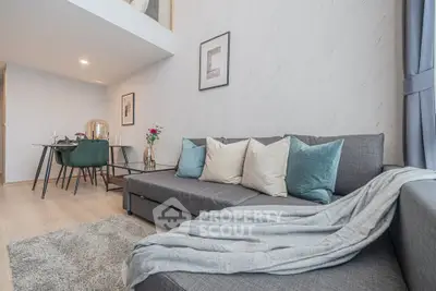 Modern living room with stylish gray sofa and elegant dining area in open layout apartment.