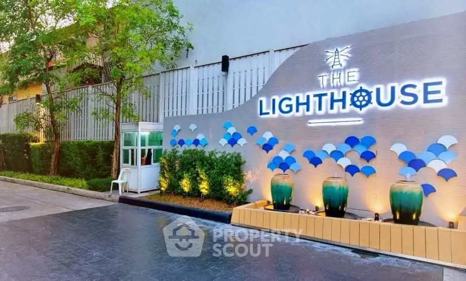 Modern building entrance with stylish signage and decorative planters at The Lighthouse.