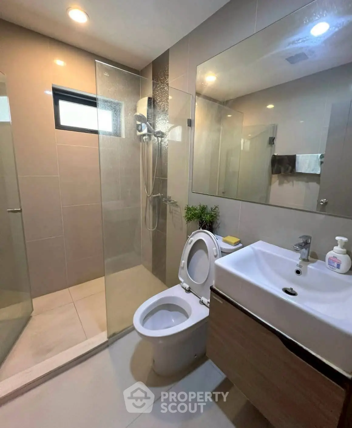 Modern bathroom with glass shower, sleek vanity, and natural light.