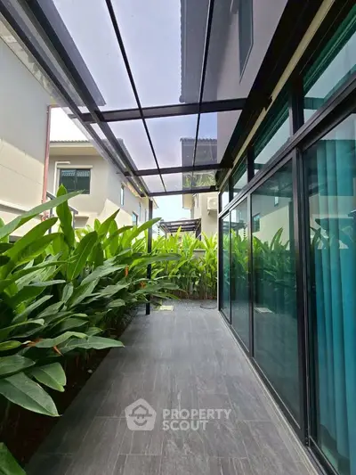 Modern home exterior with sleek glass panels and lush greenery