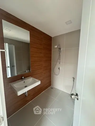 Modern bathroom with sleek design featuring wall-mounted sink and shower area.