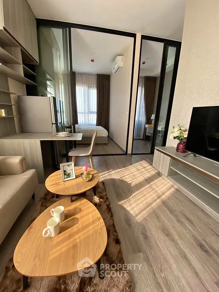 Modern living room with cozy decor and natural light, featuring a stylish workspace and comfortable seating.