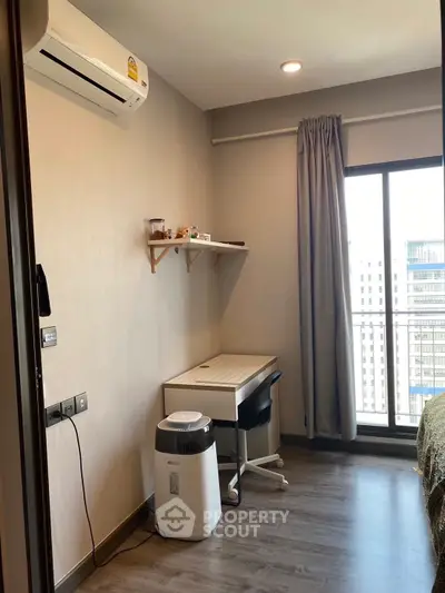 Modern study room with desk, chair, and balcony view in high-rise apartment.