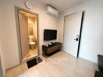 Modern apartment interior with TV, air conditioning, and bathroom entrance.
