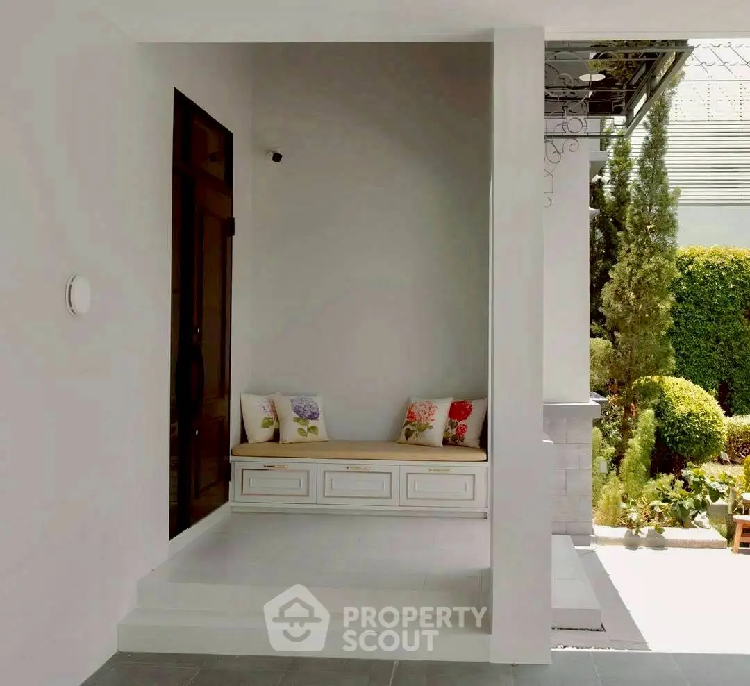 Charming entrance with cozy seating and lush garden view, perfect for relaxation and welcoming guests.