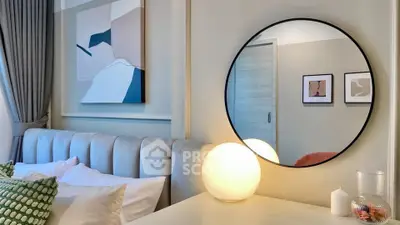 Stylish bedroom with modern decor, featuring a round mirror and elegant lighting.