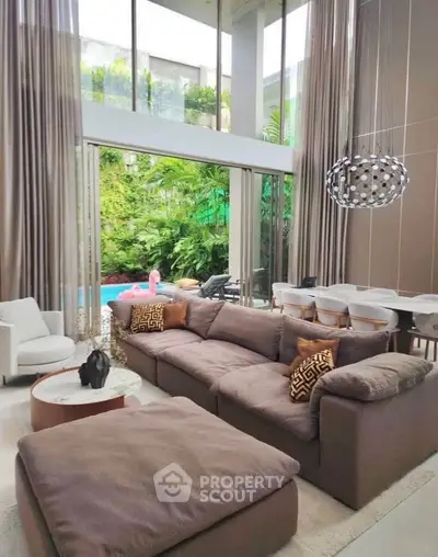 Luxurious living room with high ceilings and pool view, featuring elegant decor and modern furniture.