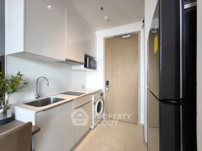 Modern kitchen with sleek cabinetry, washing machine, and stainless steel appliances in a compact layout.