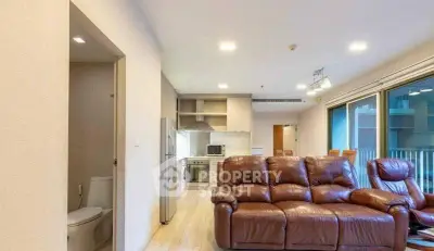 Spacious living room with leather sofa and modern kitchen in open layout apartment.