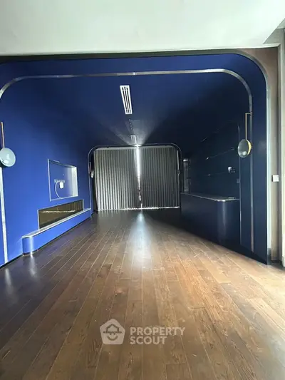 Sleek modern interior with dark wood flooring and bold blue walls, perfect for stylish living.