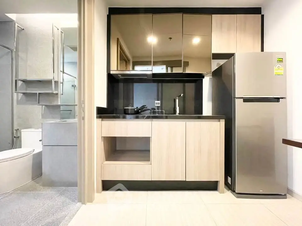 Modern compact kitchen with stainless steel fridge and sleek cabinetry
