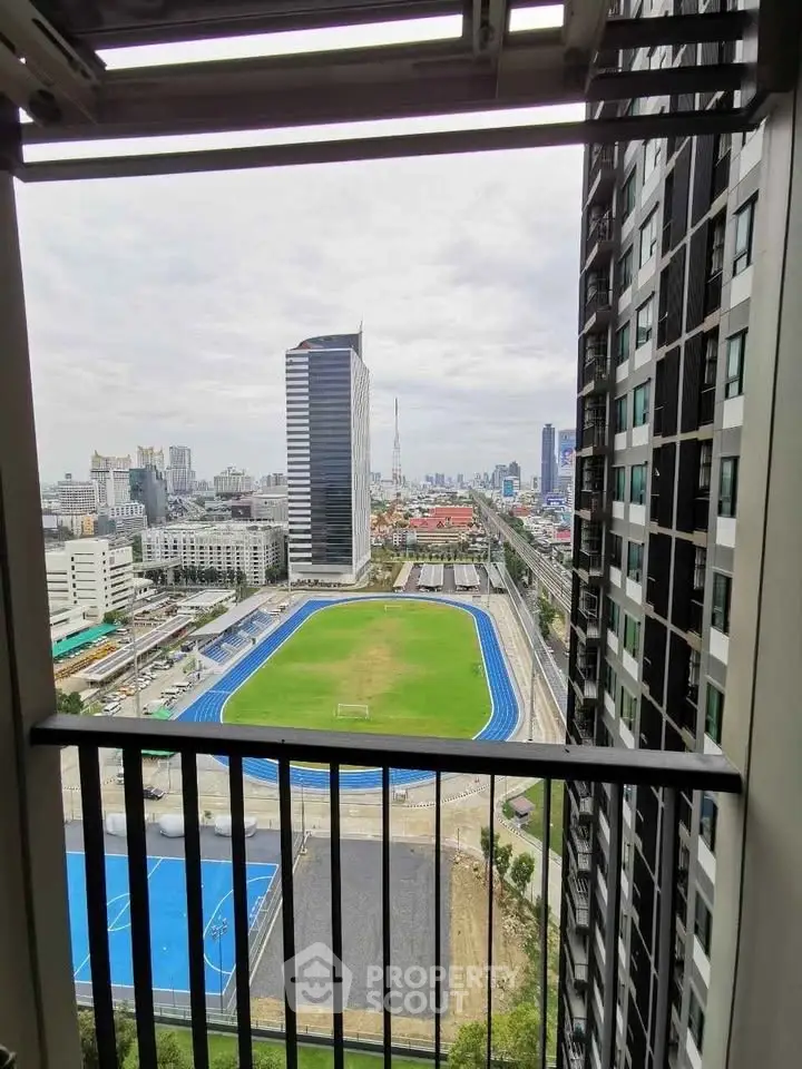 Stunning cityscape view from high-rise balcony overlooking sports field and skyline.