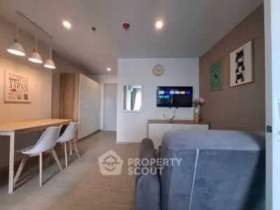 Modern living room with stylish decor and wall-mounted TV, featuring a cozy dining area.