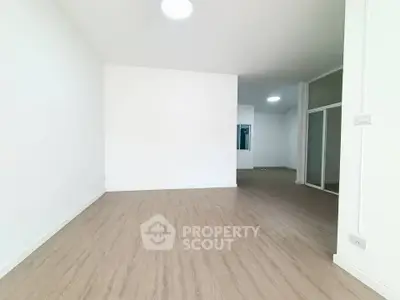 Spacious empty room with wooden flooring and white walls, ideal for customization.