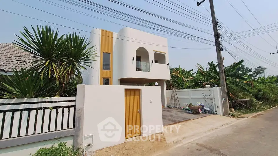 Modern two-story house with unique architectural design and lush greenery surroundings.