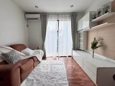 Cozy living room with modern decor, plush sofa, and natural light through large windows.