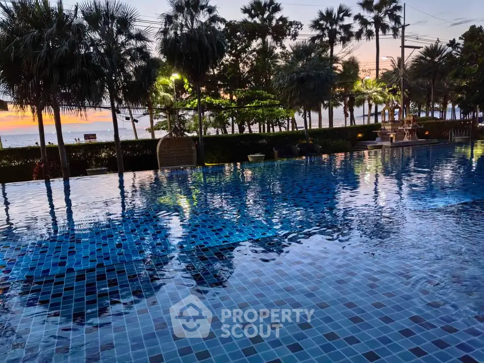 Luxurious beachfront pool with stunning sunset views and palm trees.