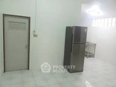 Minimalist kitchen with stainless steel fridge and tiled floor, perfect for modern living.
