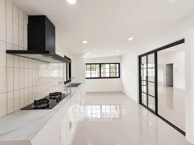 Modern kitchen with sleek gas stove and open layout, featuring large windows and bright lighting.