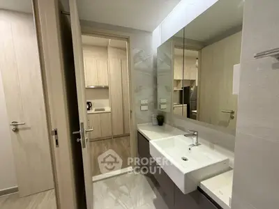 Modern bathroom with sleek sink and mirror, adjacent to a stylish kitchen.
