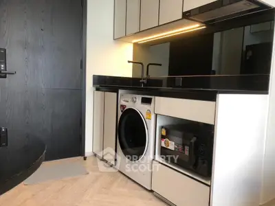 Modern kitchen with sleek appliances including washing machine and microwave, featuring elegant cabinetry and lighting.