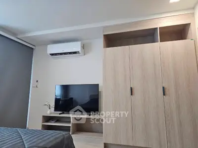 Modern bedroom with sleek wardrobe and mounted TV, featuring air conditioning and stylish decor.