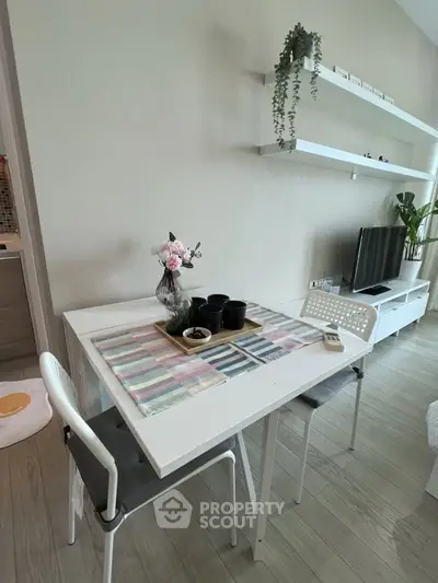 Modern dining area with sleek white table, chairs, and wall-mounted shelves in a stylish apartment.