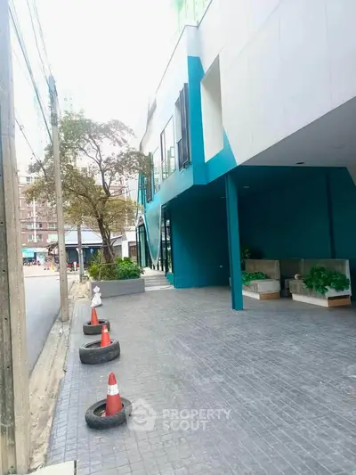 Modern building entrance with vibrant blue accents and outdoor seating area.