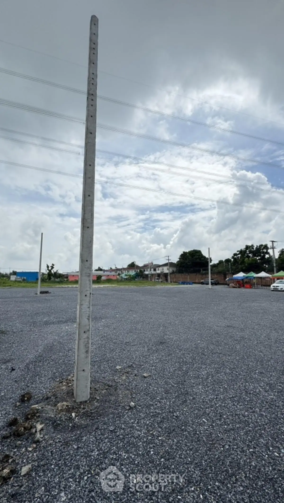Spacious gravel parking lot with utility poles under a cloudy sky