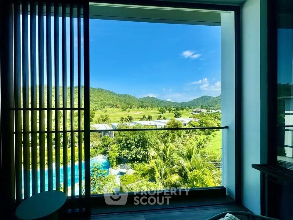 Stunning view from a modern balcony overlooking lush greenery and distant hills.