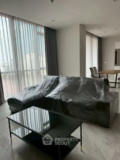 Spacious modern living room with large windows and sleek furniture, perfect for urban living.