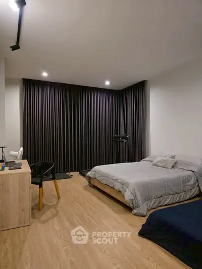 Spacious modern bedroom with elegant wooden flooring and stylish furnishings.
