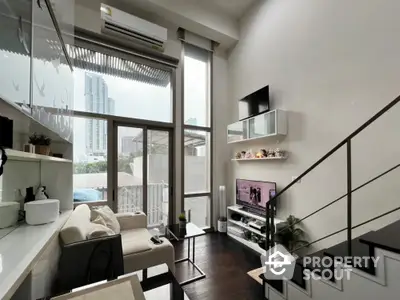 Modern loft-style living room with high ceilings and large windows offering city views.