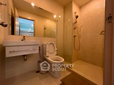 Modern bathroom with glass shower and sleek fixtures in contemporary home.