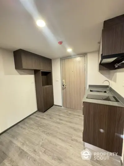 Modern kitchen with sleek cabinetry and wood flooring in a compact apartment