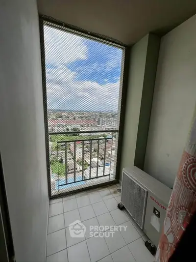 Compact balcony with safety net and city view, featuring air conditioning unit.