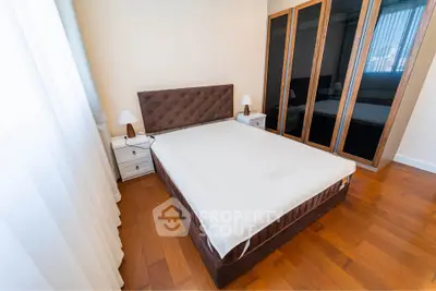 Spacious bedroom with elegant wooden flooring and modern furniture