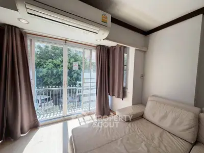 Bright living room with large windows and cozy sofa, featuring a small balcony view.