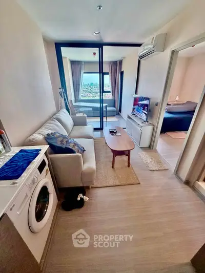 Modern living room with washing machine, cozy seating, and ocean view balcony in stylish apartment.