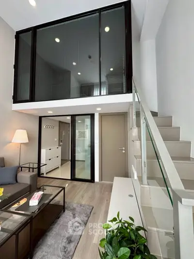 Modern loft-style living room with high ceiling and glass railing staircase
