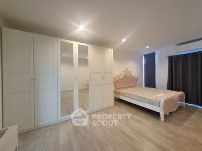 Spacious bedroom with elegant bed and large mirrored wardrobe in modern apartment.