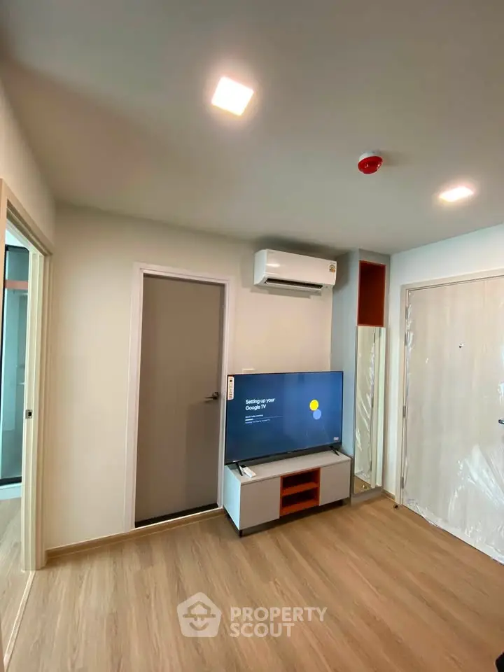 Modern living room with sleek flooring and air conditioning, featuring a flat-screen TV and stylish decor.