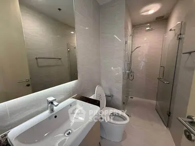 Modern bathroom with sleek fixtures and glass shower enclosure in a contemporary apartment.