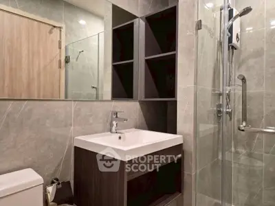 Modern bathroom with sleek design, featuring a glass shower, stylish sink, and elegant tile work.