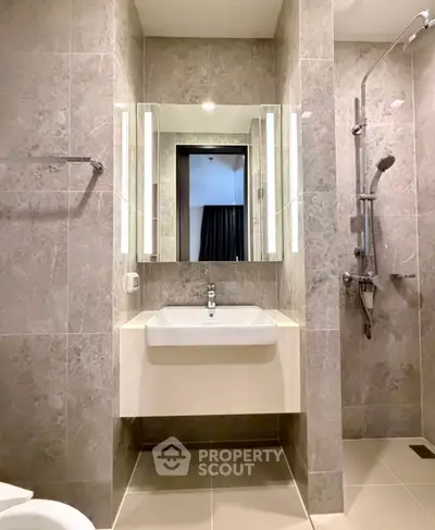 Modern bathroom with sleek design featuring a wall-mounted sink and a stylish shower area.