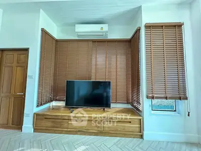 Stylish living room with wooden blinds, sleek TV unit, and air conditioning for modern comfort.